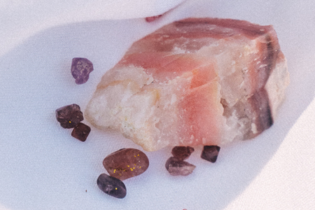 Uma grande pedra de cristal de quartzo rosa está rodeada por pedras menores.